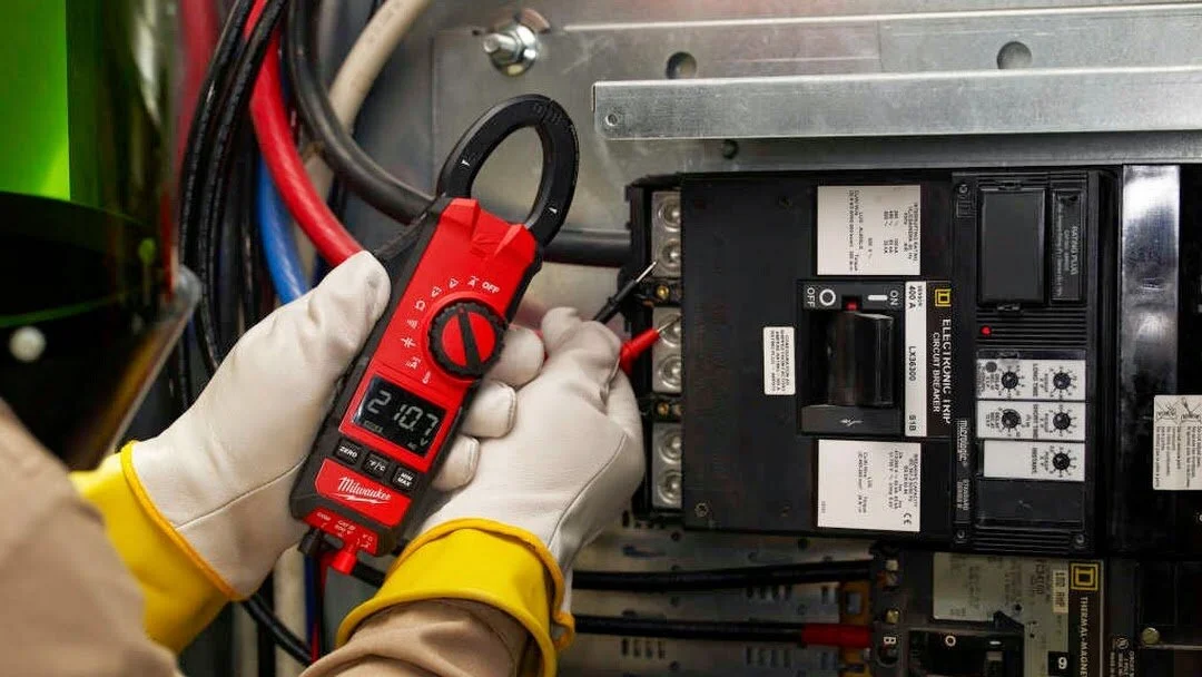 Electrician using a multimeter to test a commercial circuit breaker panel